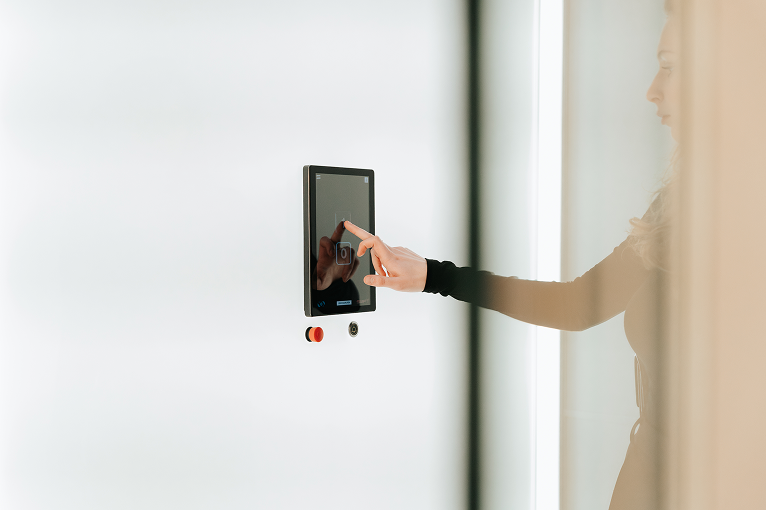 Vrouw bedient een touchscreen op een witte muur.