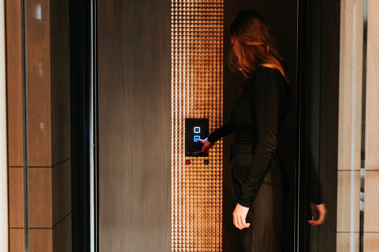 Een vrouw drukt op de knop van een moderne lift.