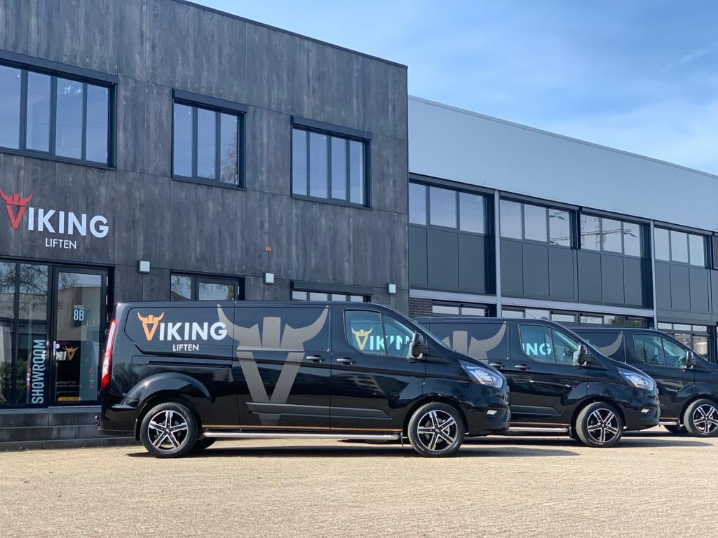 Drie zwarte voertuigen met het logo van Viking Liften voor een modern gebouw.